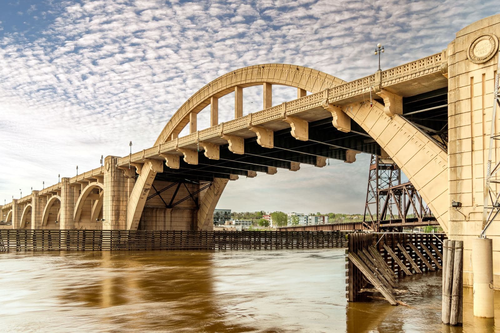 A concrete arch bridge crossing a river, with a railroad truss bridge visible alongside it
