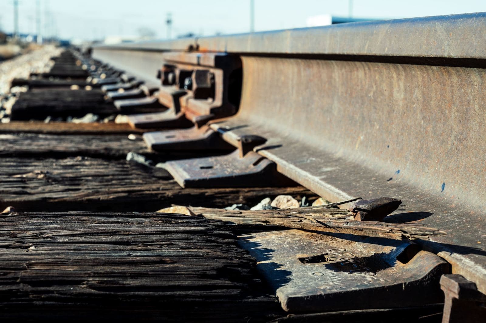 Close-up of jointed rail, tie plates, and a weathered wood crosstie at trackside